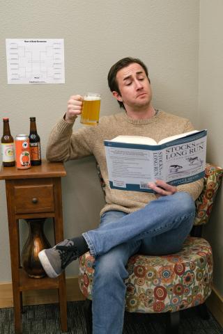 Man holding a drink reading a financial book